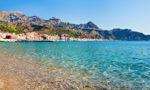 view on Taormina - very popular tourist  resort  on mountain and Gardini Naxos beach, Sicily